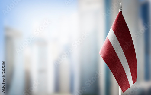 A small flag of Latvia on the background of a blurred background