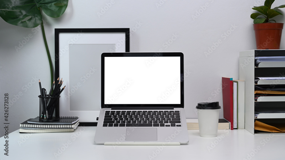 Mock up computer laptop with blank screen, notebook, empty photo frame and coffee cup on white office desk. Mock up computer laptop with blank screen, notebook, empty photo frame and coffee cup on white office desk.