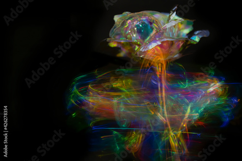 Blurred crystal glass roses on colored light background in black backdrop.