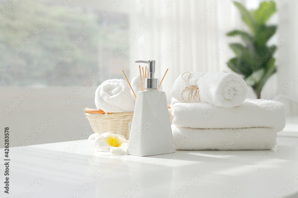 Soap dispenser and spa towel ,Roll up of white towels on white table with copy space,towels studio shot on white table