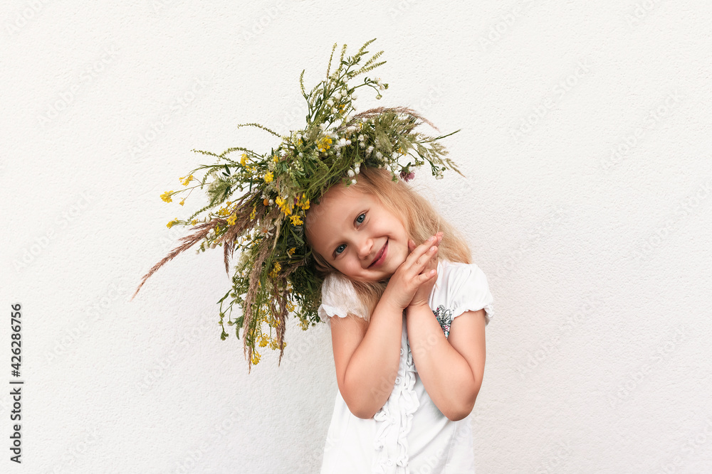 Little girl in a wreath of flowers on a white background. The child in ...