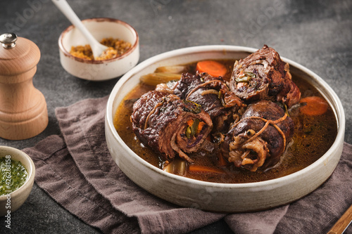 Dish of beef, bacon and pickle roulades in gravy seasoned with vegetables for a traditional regional German dinner. German traditional cuisine beef roulade with bacon and vegetables