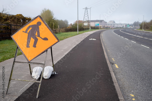 Road works oragne sign by a motorway. Construction and repair on a road warning. Transportation industry