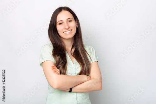 Portrait of young cheerful woman with crossed arms standing over white background