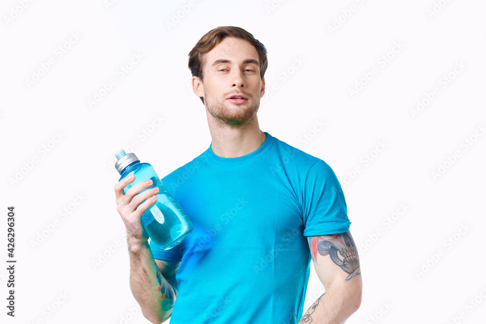 athlete in a blue t-shirt with a bottle of water on a white background and a tattoo on his arm athlete in a blue t-shirt with a bottle of water on a white background and a tattoo on his arm