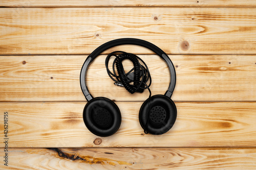 Black headphones with wire on wooden background