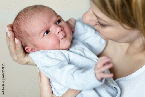 A newborn baby in her mother's arms is looking at her attentively. Motherhood and caring for a new life. Close-up.