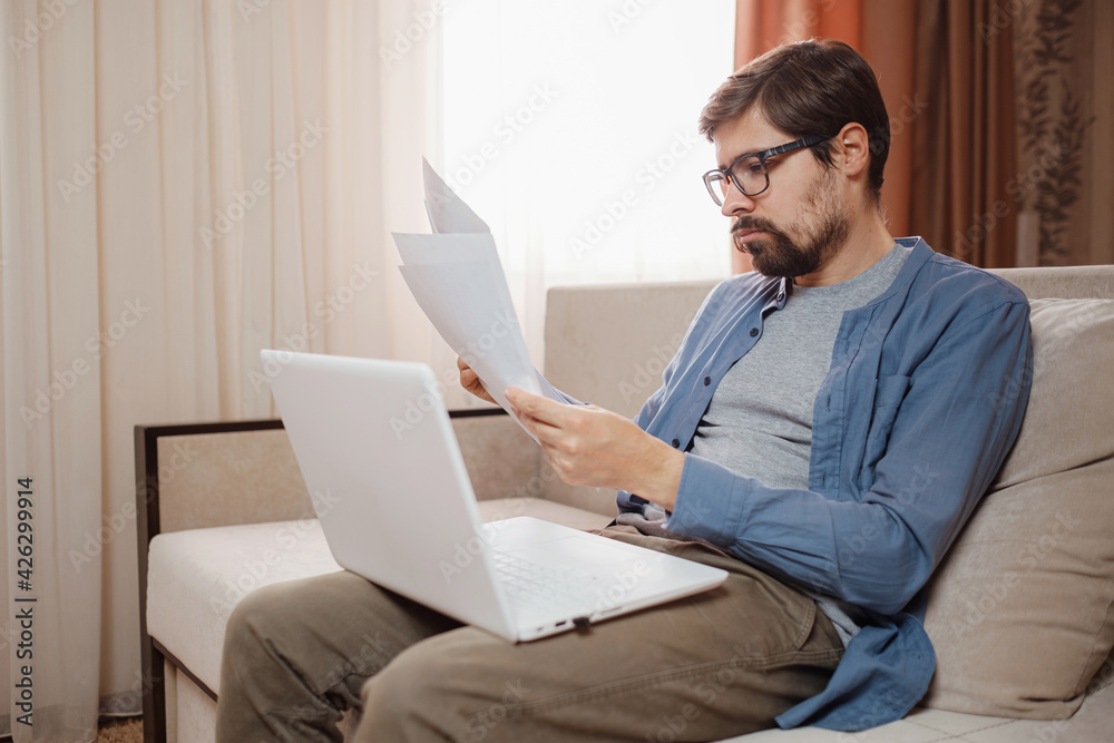 Entrepreneur works with a laptop and keeps a document in a home office Entrepreneur works with a laptop and keeps a document in a home office