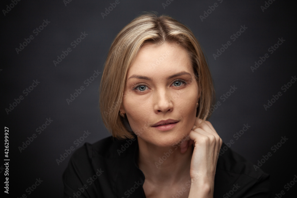 Beautiful middle-aged woman on a gray background in a black blouse. Beautiful middle-aged woman on a gray background in a black blouse.