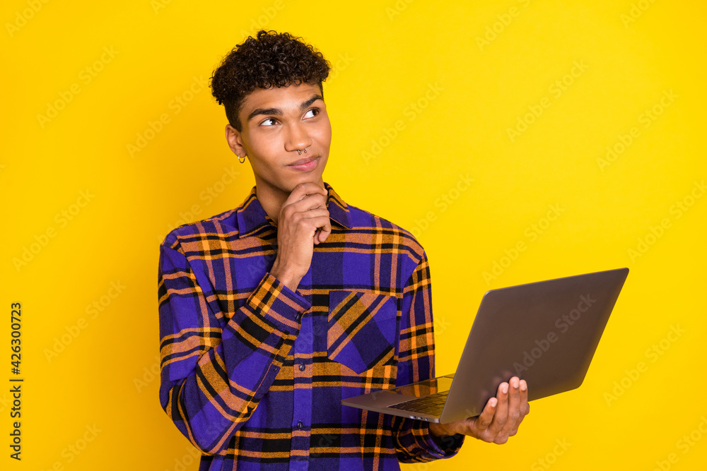 Photo portrait of young man working on computer thinking looking empty space isolated vibrant yellow color background Photo portrait of young man working on computer thinking looking empty space isolated vibrant yellow color background