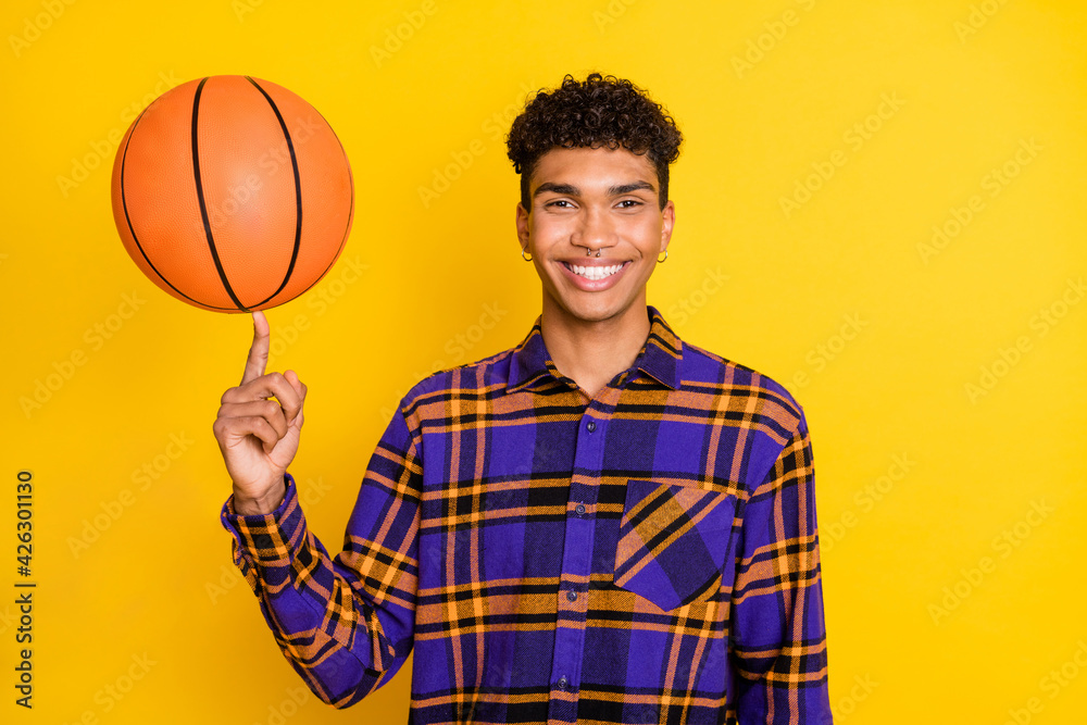 Photo portrait of young man playing with ball smiling in checkered shirt isolated vibrant yellow color background