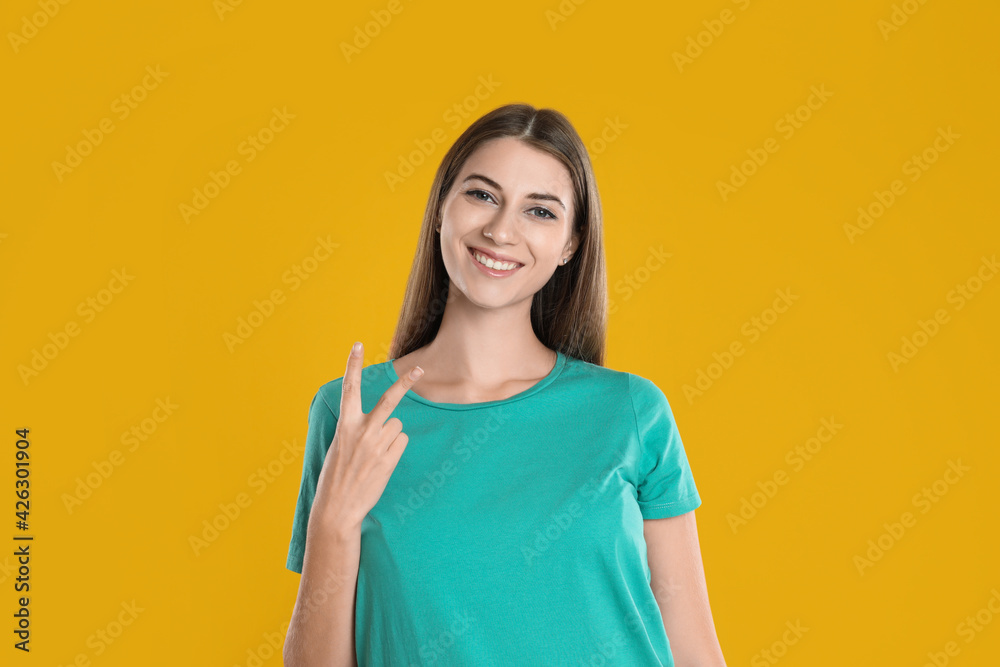 Woman showing number two with her hand on yellow background Woman showing number two with her hand on yellow background