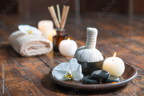 Spa background. Towel, candles, flowers, aroma sticks, massaging stones and herbal balls. Massage, oriental therapy, wellbeing and meditation.