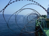 View of razor wire coils fitted around the shipside to protect the ship from pirates