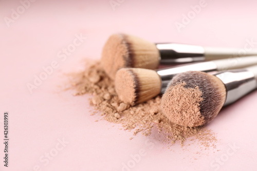 Different makeup brushes with crushed cosmetic product on pink background, closeup. Space for text