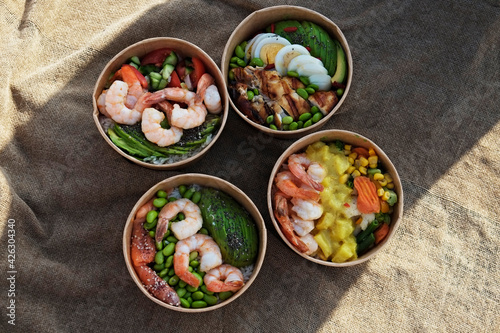 Clean eating diet concept. Four takeout bowls for different dieting habits, pescatarian and carnivore. Disposable paper containers with healthy food. Close up, copy space, top view, background.