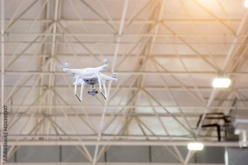 White drone in motion flying from the ceiling inside the building. White drone in motion flying from the ceiling inside the building.