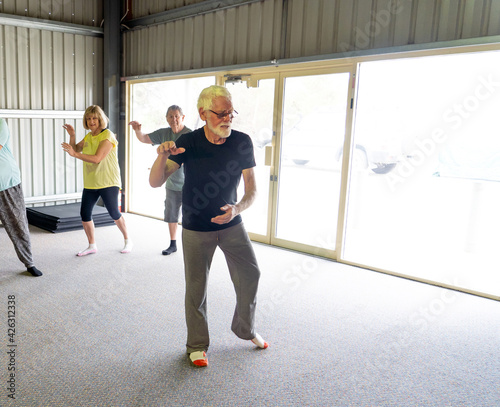 Group of elderly senior people practicing Tai chi class in age care gym facilities.