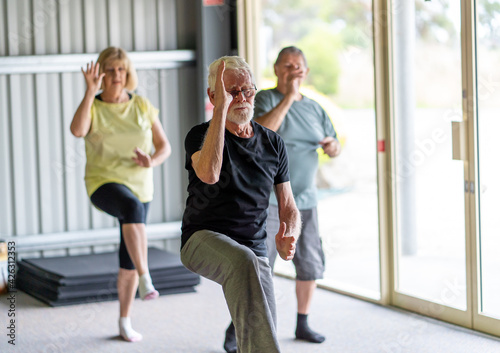 Group of elderly senior people practicing Tai chi class in age care gym facilities. photo