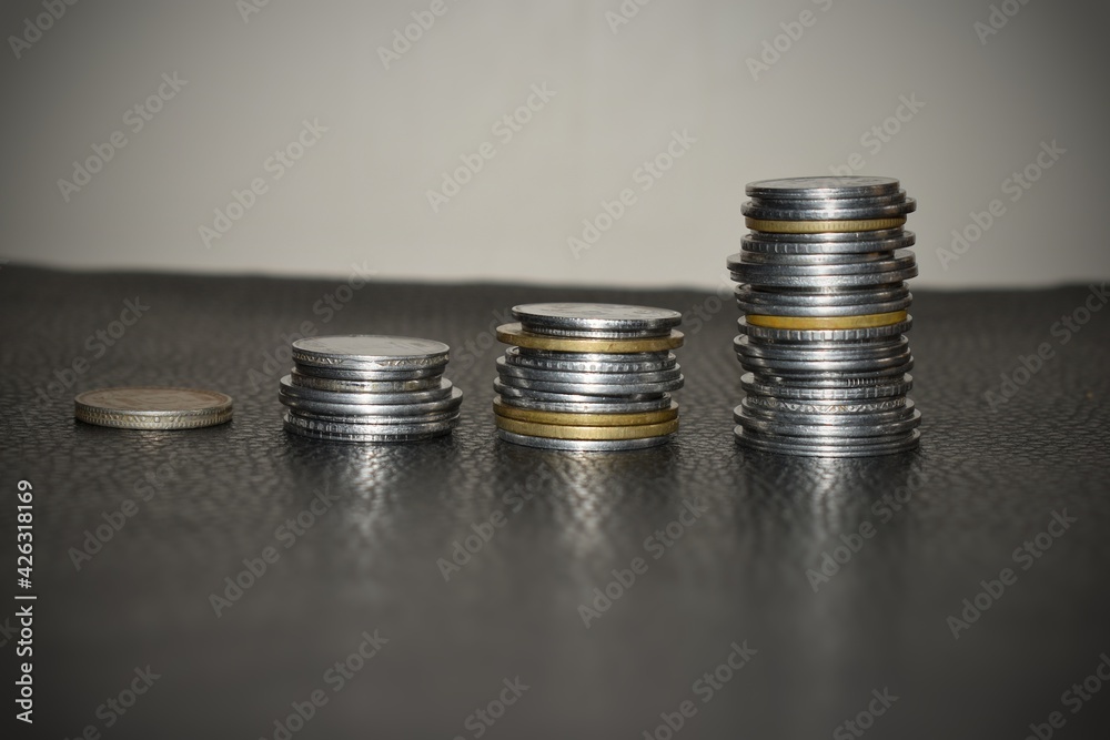 Coins stacks with a growth multicolor graph on silver sparkling bokeh background. Financial growth concept.E Coins stacks with a growth multicolor graph on silver sparkling bokeh background. Financial growth concept.E