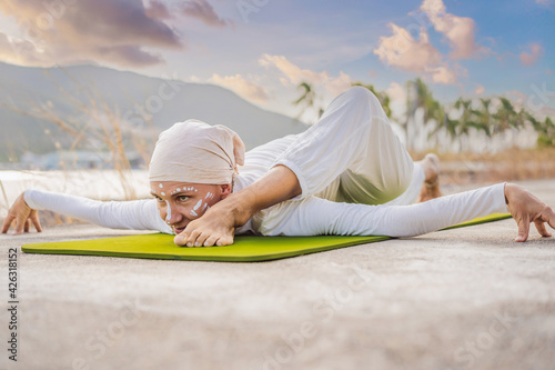 Kundalini yoga woman in white clothes and turban practices yoga kundalini on the background of the sea, mountains and sunset. Fighting face painting of the Indians shows her inner world. Visual © galitskaya