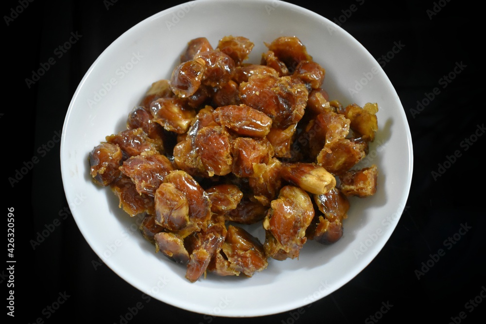 Bowl of pitted dates isolated on black background, top view, india.