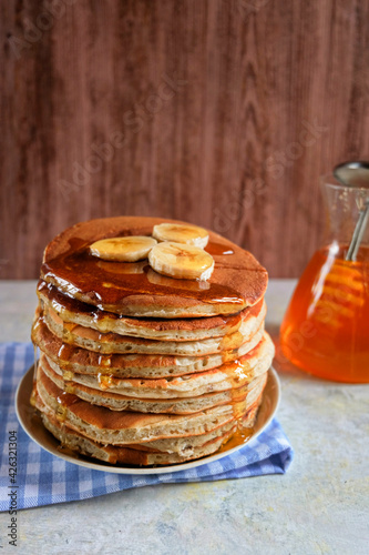 Pancakes with banana,walnut and muple syrup for a breakfast on wooden background closeup. Copy space. Vertical...