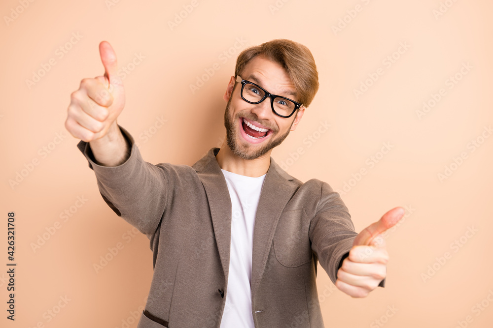 Photo of optimistic nice blond hair man show thumb up wear spectacles grey jacket isolated on beige background Photo of optimistic nice blond hair man show thumb up wear spectacles grey jacket isolated on beige background