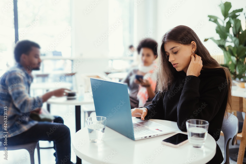 Portrait of female student using net-book while sitting in cafe Portrait of female student using net-book while sitting in cafe