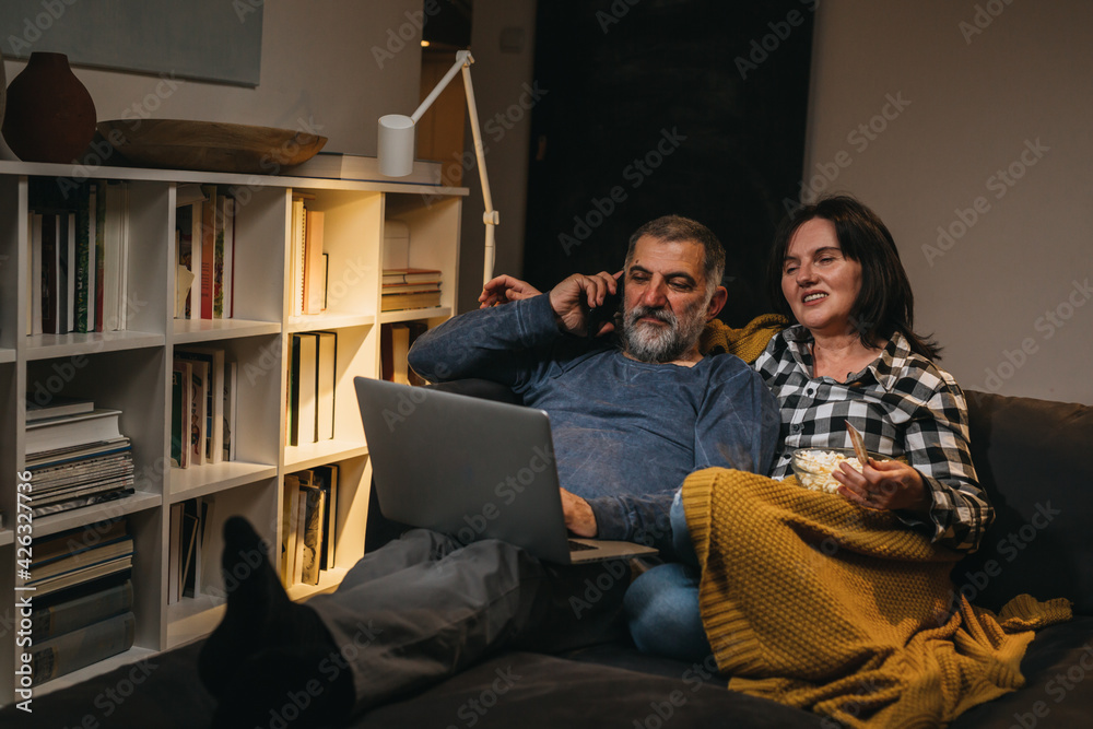 middle age romantic couple enjoying time together at home. they are using laptop computer for online shopping
