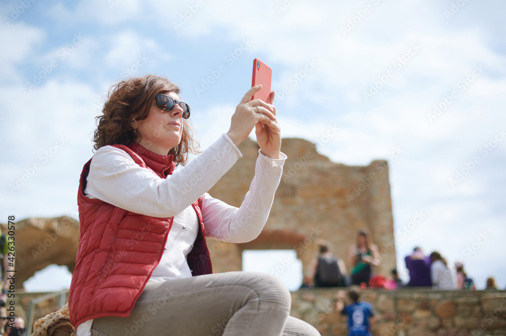 Middle-aged woman taking photo with her smart phone in archaeological ruins Middle-aged woman taking photo with her smart phone in archaeological ruins