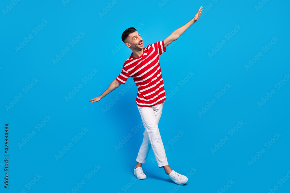 Fototapeta premium Full body photo of funky happy cheerful man look empty space hands wings isolated on blue color background