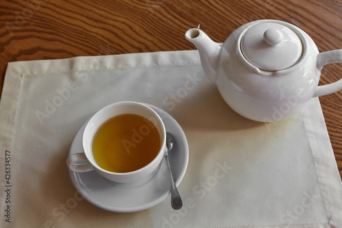 The table is set for tea. A teapot and a tea cup are placed on the table overlooking the terrace
