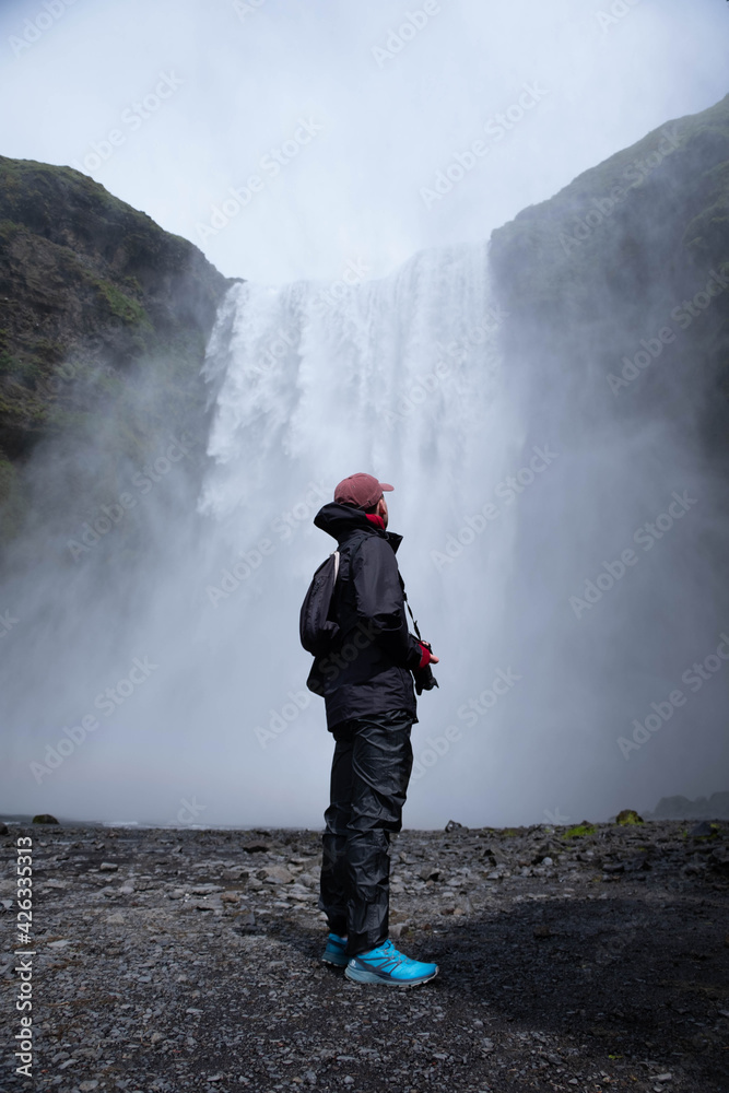 person with a backpack looking a waterfall person with a backpack looking a waterfall