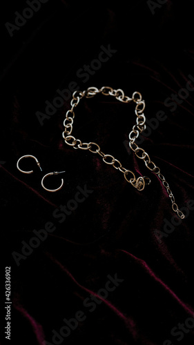 gold chain and earrings on dark red background