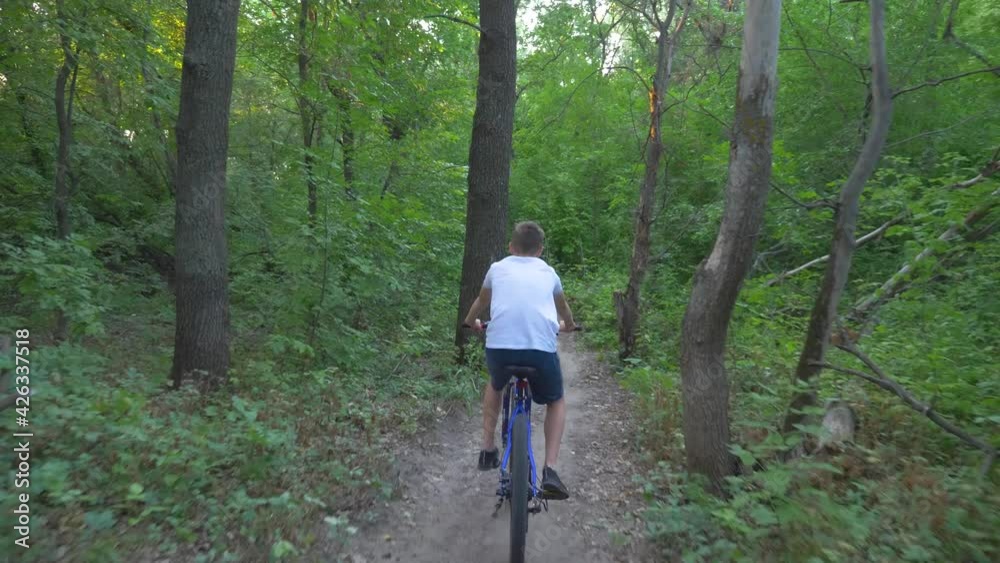 A happy child rides a bicycle in a park in the open air. Cycling on a path in the woods. Active rest of the child. Healthy lifestyle, children's sports. A happy child rides a bicycle in a park in the open air. Cycling on a path in the woods. Active rest of the child. Healthy lifestyle, children's sports.