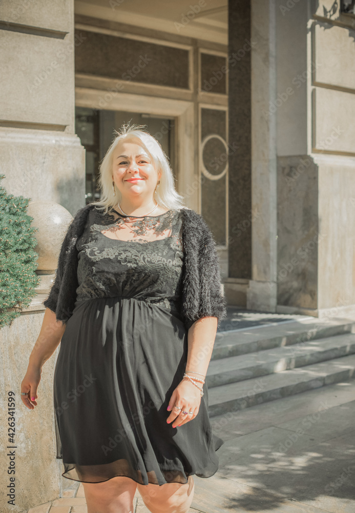 Woman of plus size, American or European appearance walks at the city enjoying life. A young lady with excess weight, xl size at the center of the city. Natural beauty