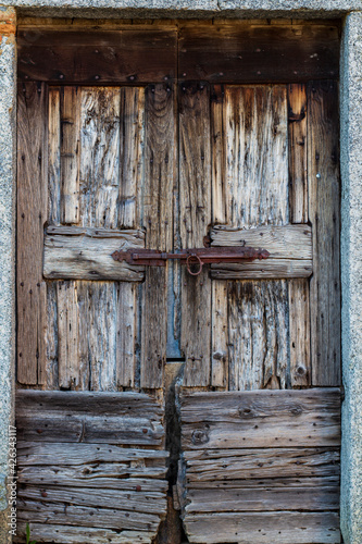 Old wooden door in Italy with iron sliding lock detail. Copy space