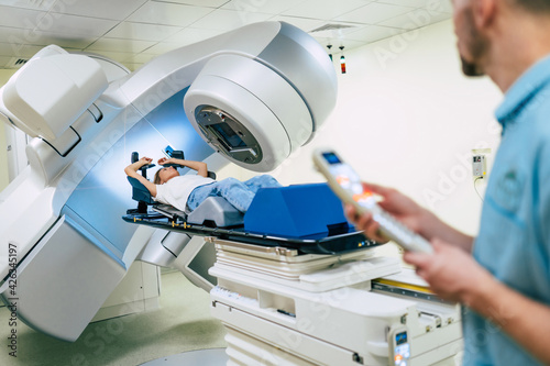 Cancer treatment in a modern medical private clinic or hospital with a linear accelerator. Professional doctors team working while the woman is undergoing radiation therapy for cancer photo