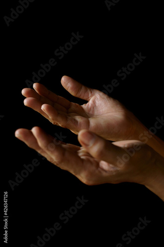 Praying hands of an old Indian Catholic woman isolated on a plain black background. (ID: 426347126)