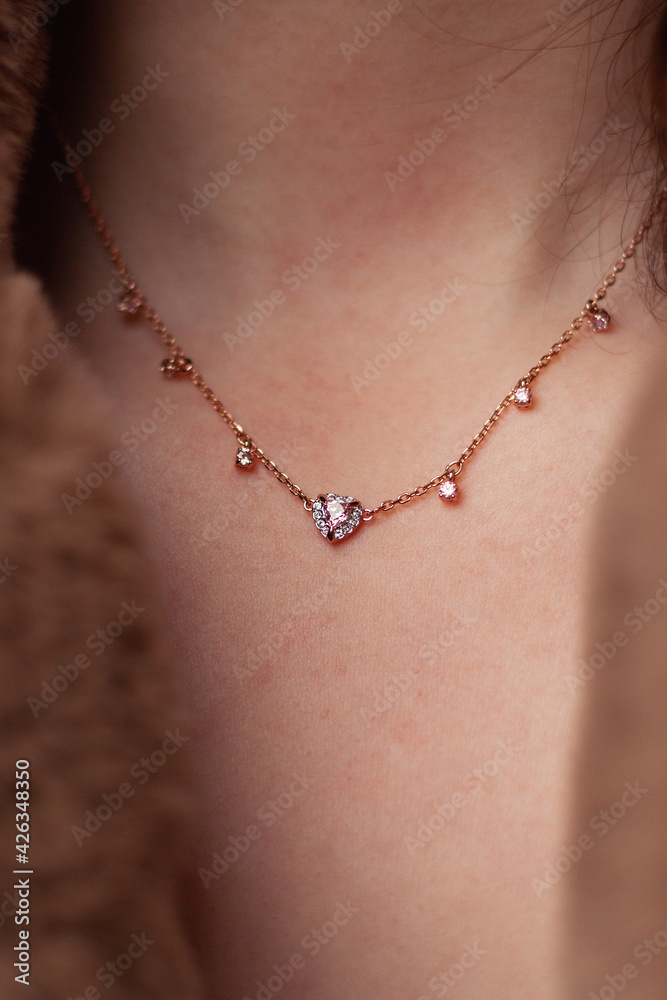Gold necklace with gemstone close-up on neck. Elegant attire. Close perspective. Warm outfit, spring vibes. Gold necklace with gemstone close-up on neck. Elegant attire. Close perspective. Warm outfit, spring vibes.