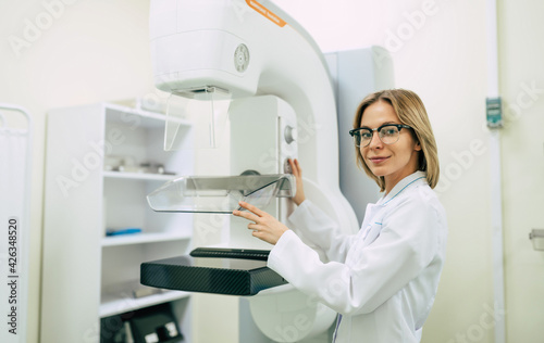 Cute professional woman doctor is working with modern Mammography X-Ray System Machine in a hospital or private clinic. Cancer and disease female treatment concept