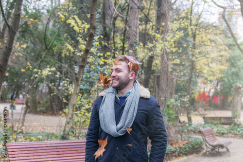 young man smiling with dried leaves on his head