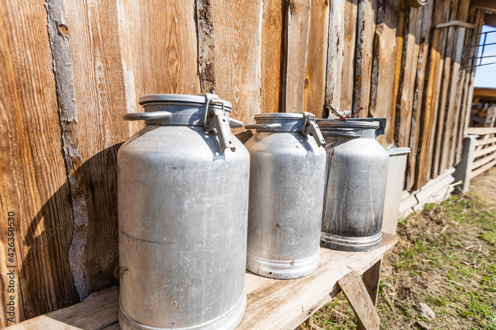 An old metal milk can, next to a large wooden log. Perfect shot to describe country life on a farm. An old metal milk can, next to a large wooden log. Perfect shot to describe country life on a farm.