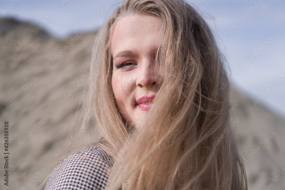 Beauty portrait of a young blond girl in a vintage dress. She is posing on a sandy landscape. Beauty portrait of a young blond girl in a vintage dress. She is posing on a sandy landscape.