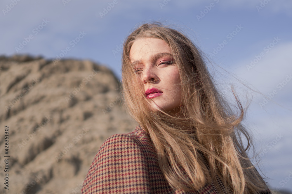 Beauty portrait of a young blond girl in a vintage dress. She is posing on a sandy landscape. Beauty portrait of a young blond girl in a vintage dress. She is posing on a sandy landscape.