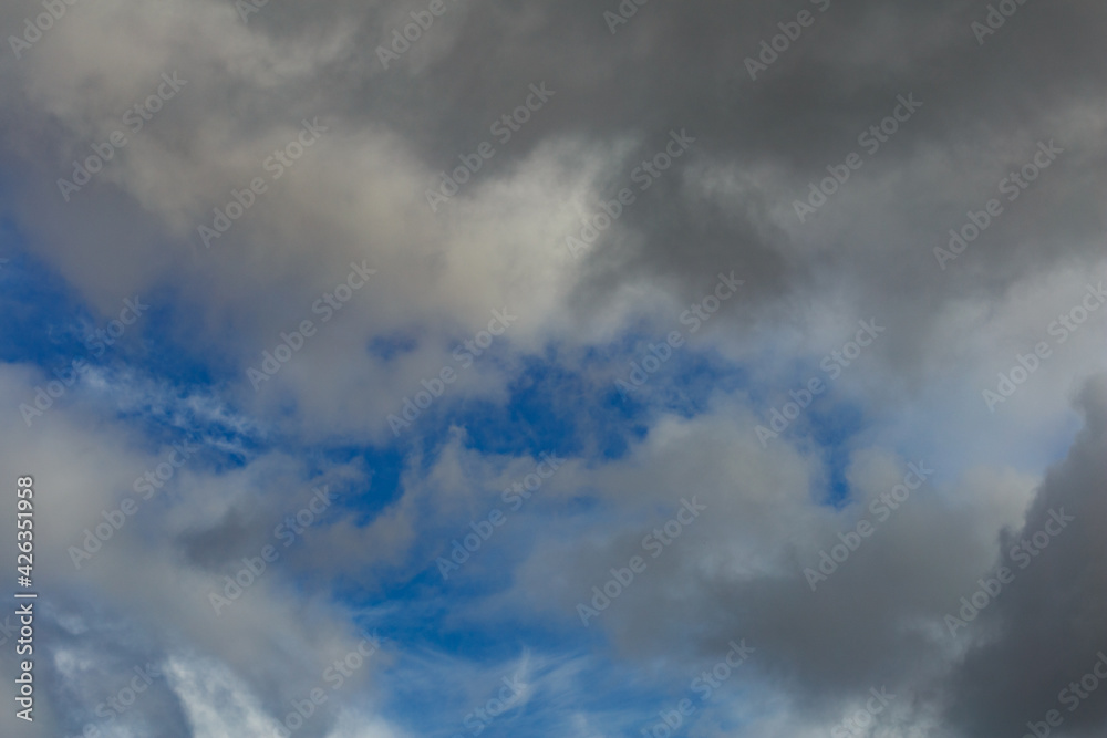 Dark storm clouds on a bright blue sky. Sky patterns background 2021.