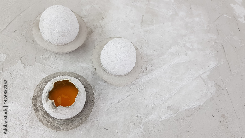 concrete Easter egg with a bright yellow yolk standing on a gray background, space for text concrete Easter egg with a bright yellow yolk standing on a gray background, space for text