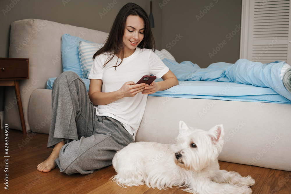 Happy young woman playing with her dog in bedroom Happy young woman playing with her dog in bedroom