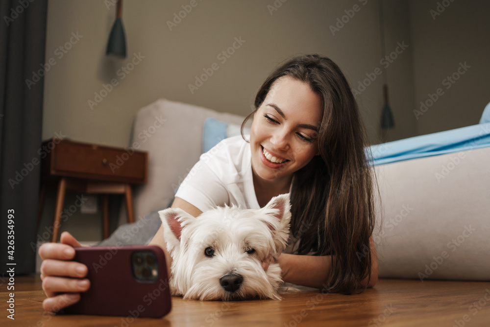 Happy young woman playing with her dog in bedroom Happy young woman playing with her dog in bedroom